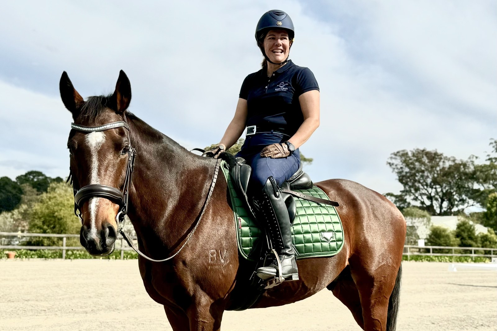 Rachel smiling from the saddle on her horse Wylie in the arena